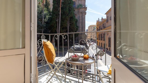 A balcony with a metal railing, a small table, and a chair. - Bright apartment with views of the Cathedral (Málaga)