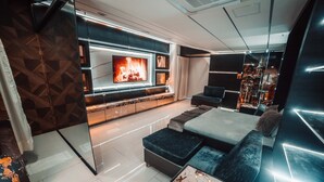 Una sala de estar moderna con un televisor grande, una chimenea y una zona de estar acogedora.