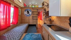 A compact RV interior with a kitchenette, a bed, and a dining area. - Tiny House Martin - Pet Friendly (Leadville)