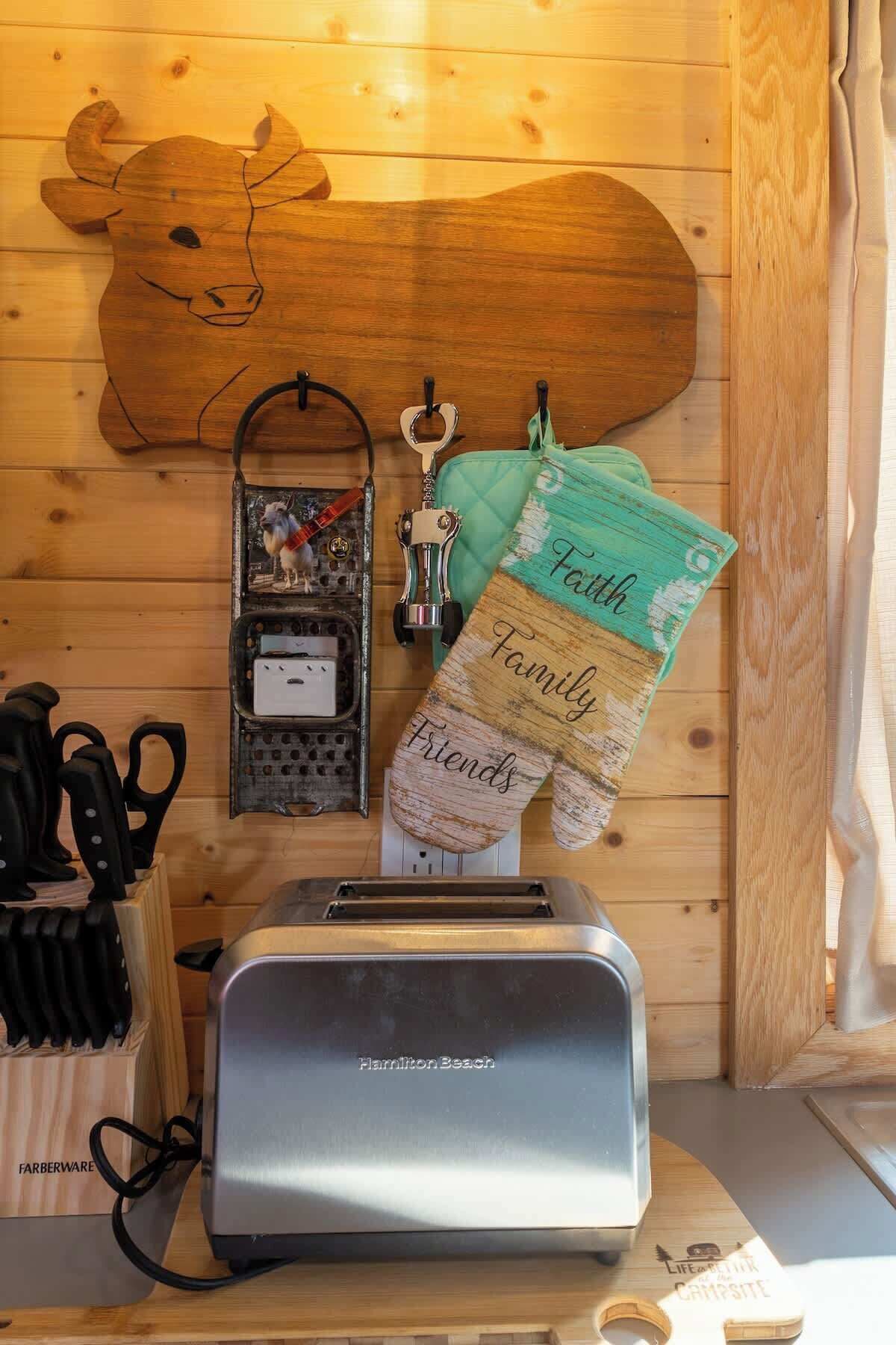 Eine Küchenzeile mit Toaster, Messerblock, einer dekorativen Holzform und einem grünen Tuch mit der Aufschrift 'Family Friends'.