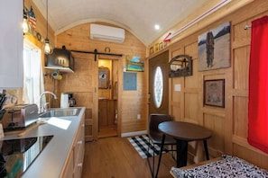 Compact kitchen with toaster, sink, and dining area with a round table and two chairs.