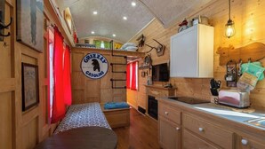 A cozy cabin interior with a kitchenette, a dining area, and a sleeping space. - Tiny House Martin - Pet Friendly (Leadville)