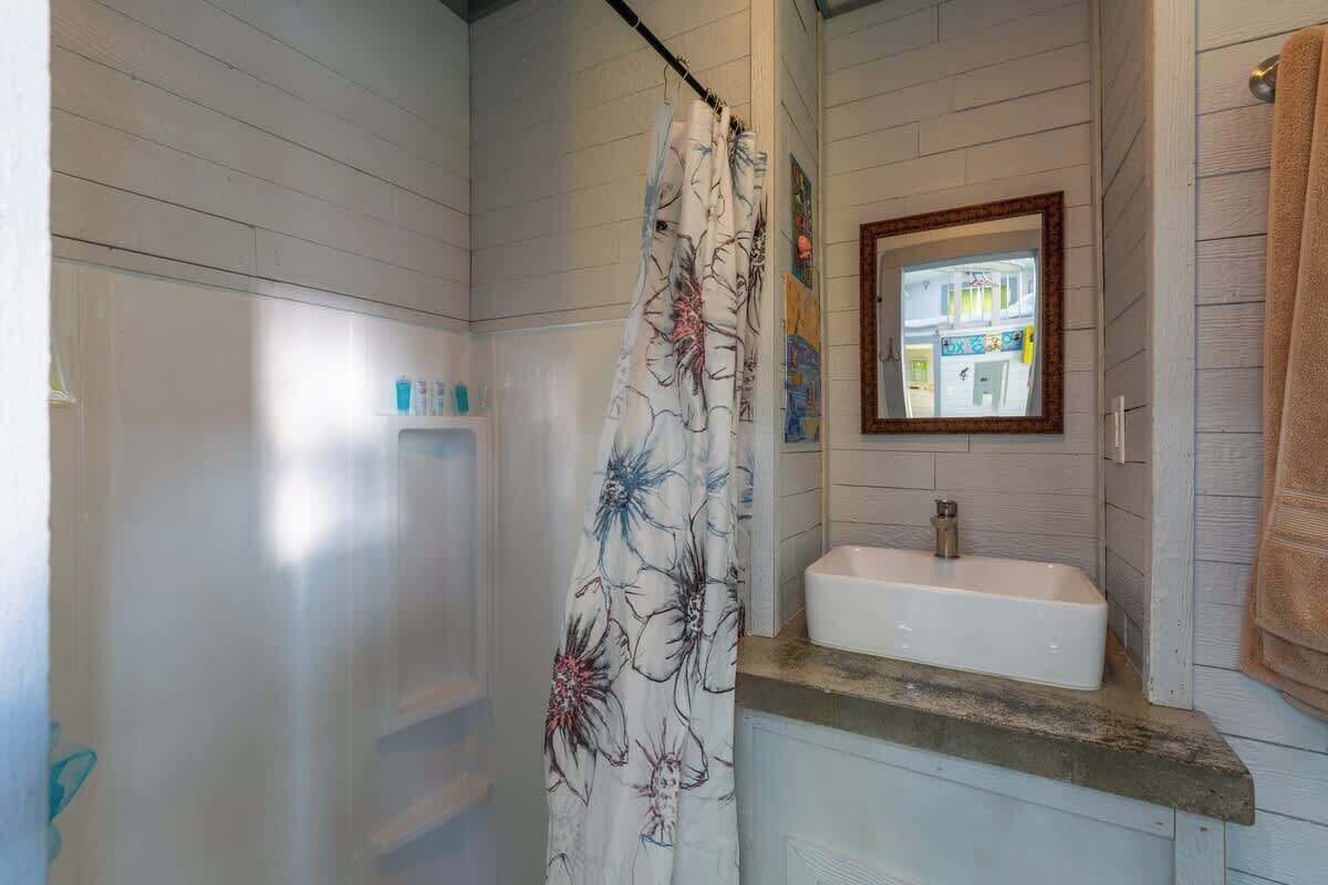 A bathroom with a shower, a sink, and a mirror.