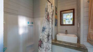 A bathroom with a shower, a sink, and a mirror.