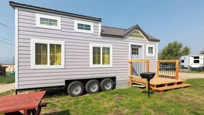 Una casa móvil con diseño de dos pisos, un porche delantero y una puerta corrediza.