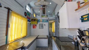 Una cocina compacta con un banco integrado, una cafetera y un pequeño comedor con mesa.
