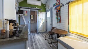 Una cocina con piso de madera, un lavamanos, una estufa y un comedor con mesa y sillas.