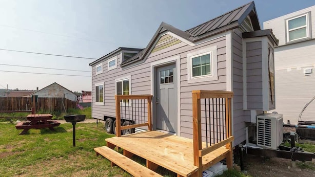 Una casa móvil con una pequeña terraza y una mesa de picnic.