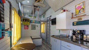 Una cocina compacta con armarios blancos, un banco de madera y una cafetera.
