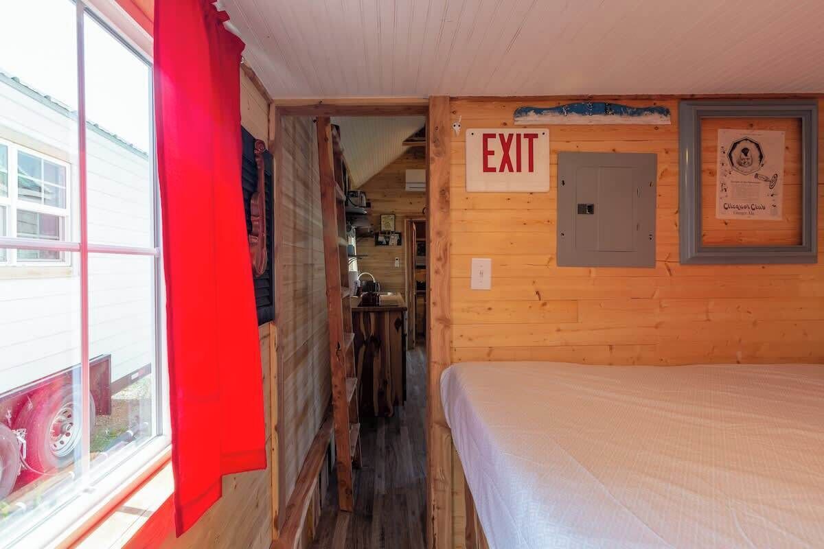 Habitación de cabaña de madera con una cama, un letrero de salida y un certificado enmarcado en la pared.