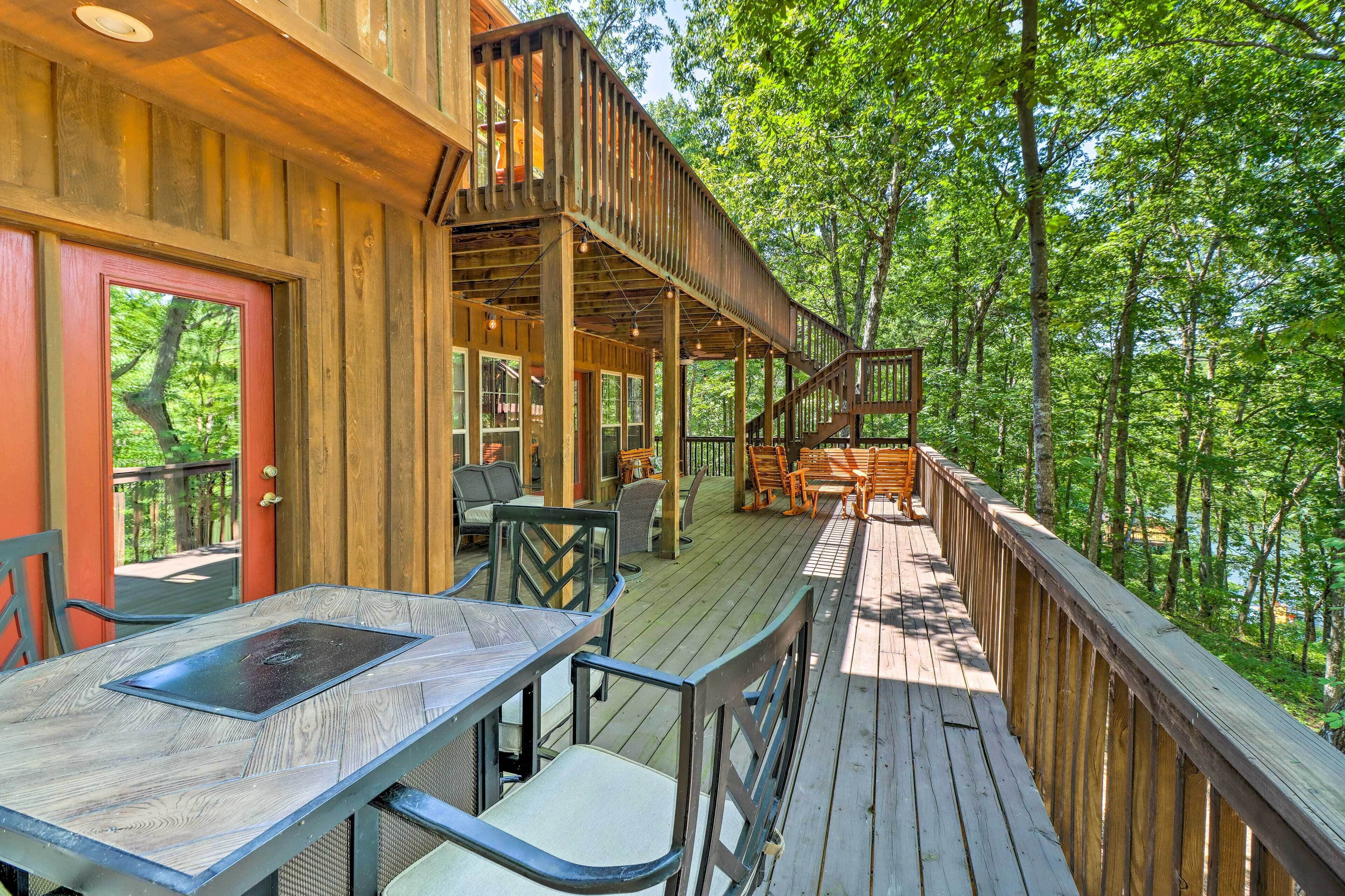 Une terrasse en bois avec des sièges extérieurs et une vue sur une zone boisée.