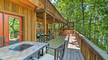 Une terrasse en bois avec des sièges extérieurs et une vue sur une zone boisée.