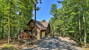 A rustic cabin with a stone foundation, wooden exterior, and a gravel driveway leading to a wooden deck. - Heber Springs Family Lake House: Fire Pit & Decks (Heber Springs)