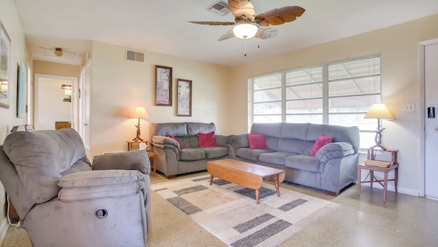 A living room with a ceiling fan, two couches, a coffee table, and a rug. - Pets Welcome: Cozy Home w/ Pool in Margate! (Margate)