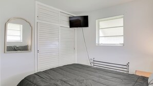 A bedroom with a bed, a television mounted on the wall, a window with blinds, a wardrobe, and a mirror. - Pets Welcome: Cozy Home w/ Pool in Margate! (Margate)