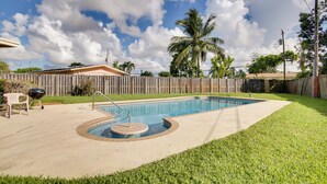 A backyard with a swimming pool, a wooden fence, and a grassy lawn. - Pets Welcome: Cozy Home w/ Pool in Margate! (Margate)