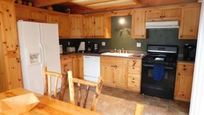 Une cuisine en bois équipée d’un réfrigérateur, d’une cuisinière et de meubles de rangement en bois.