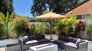 Een terras buiten met een modulaire bank, een bijzettafeltje en een parasol.