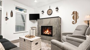 A modern living room with a fireplace, comfortable seating, and a flat-screen TV. - Expansive Ocean Views From Home and Hot Tub, Pet Friendly, Private Deck, Fireplace, Steps From Beach (Depoe Bay)