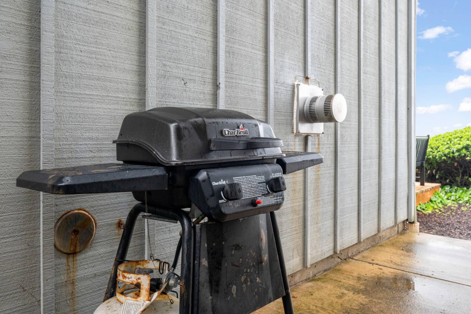 A Char-Broil grill with a control panel, a gas tank, and a vent.