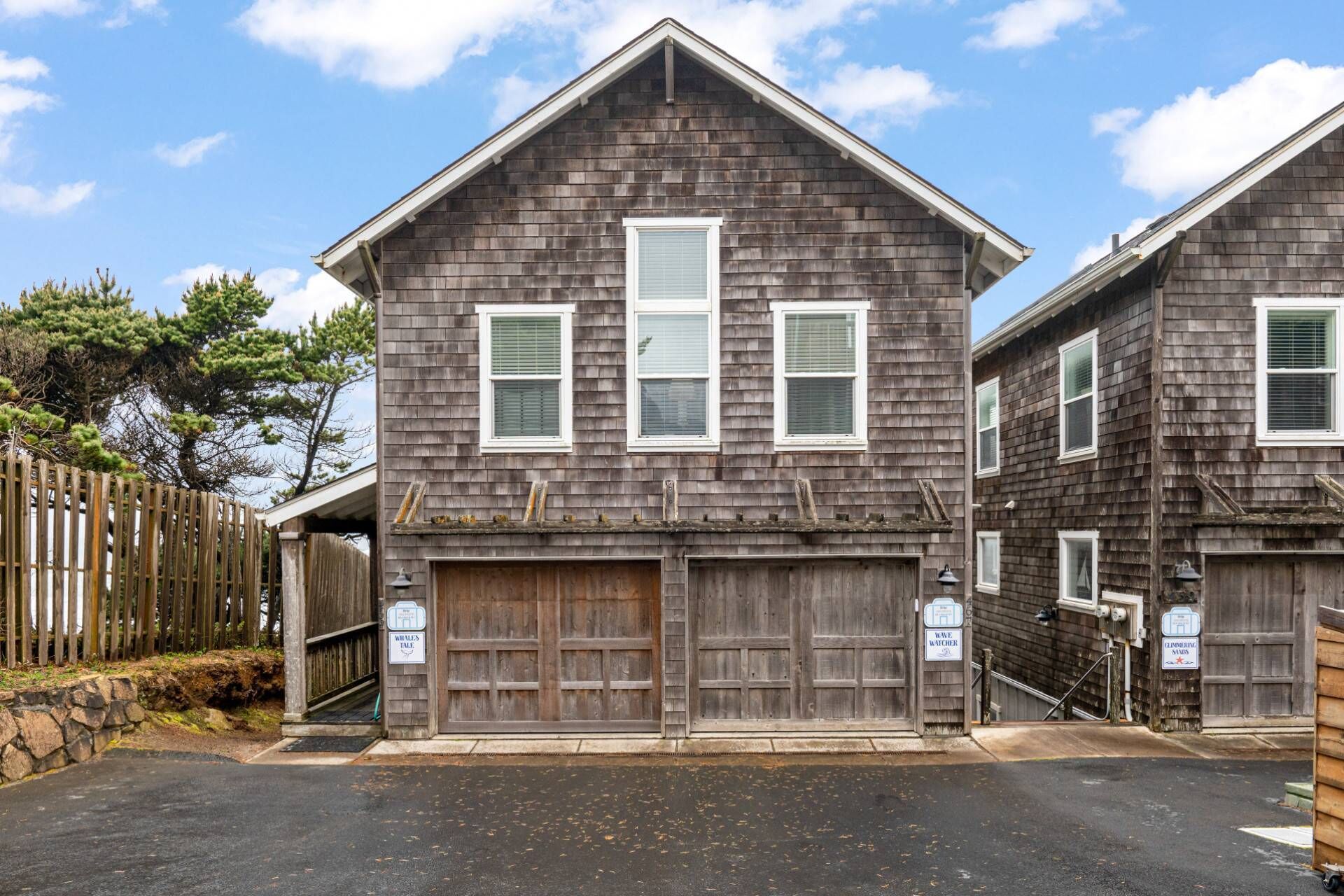 A two-story house with a dark wooden exterior, white trim, and a garage with a wooden door.