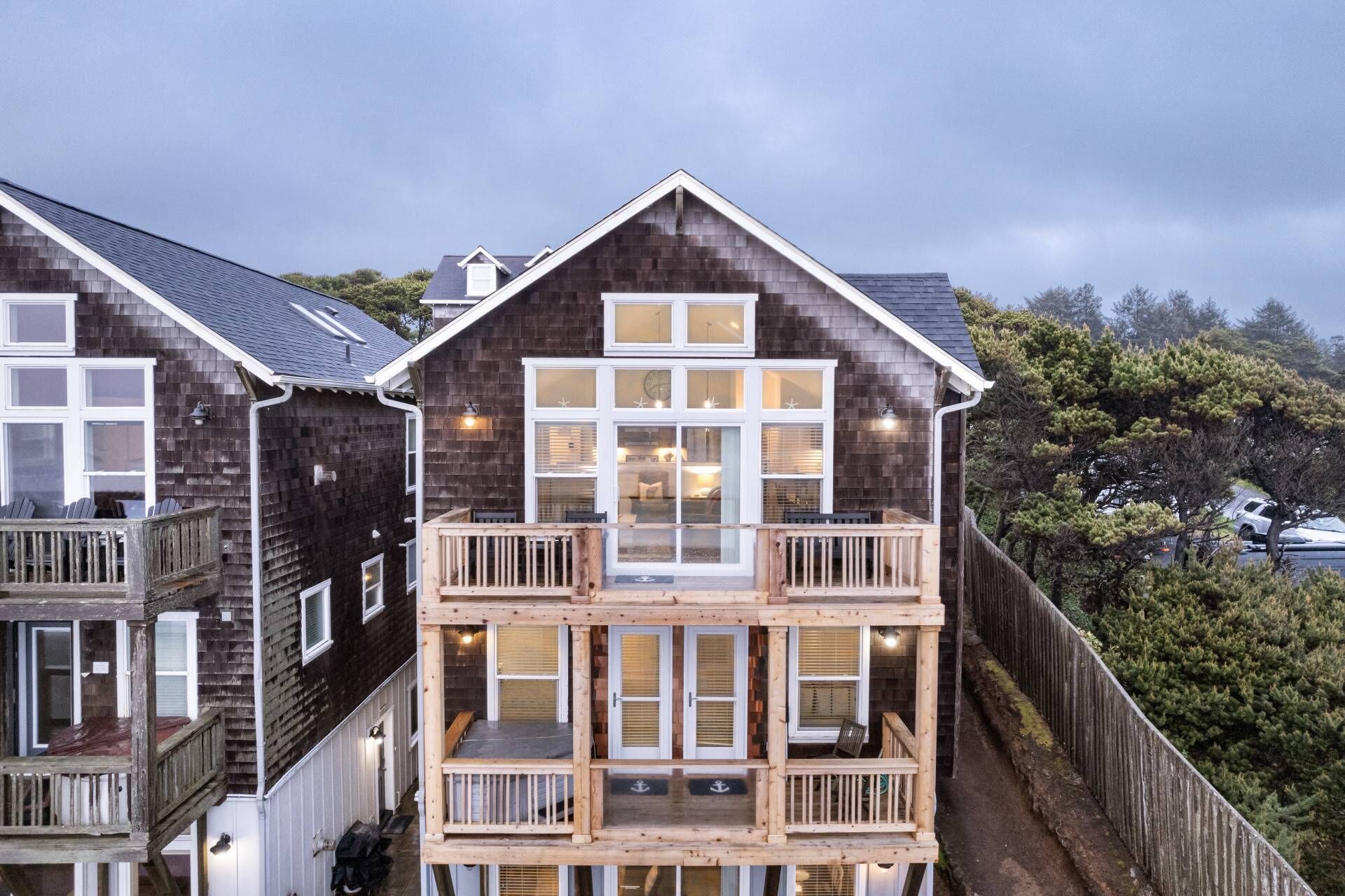 A two-story house with a balcony, large windows, and a wooden deck.