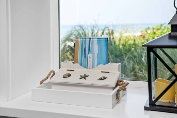 A white box with a guest book on a windowsill, a small shelf with seashells, and a black lantern. - Boundless Ocean Views From Home and Hot Tub, Pet Friendly, Private Deck, Fireplace, Steps to Beach (Depoe Bay)