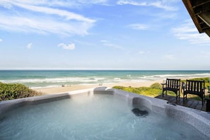 A hot tub with a view of the beach and ocean.