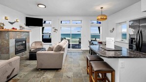 A modern kitchen with a view of the ocean, a fireplace, and a dining area with a view. - Boundless Ocean Views From Home and Hot Tub, Pet Friendly, Private Deck, Fireplace, Steps to Beach (Depoe Bay)