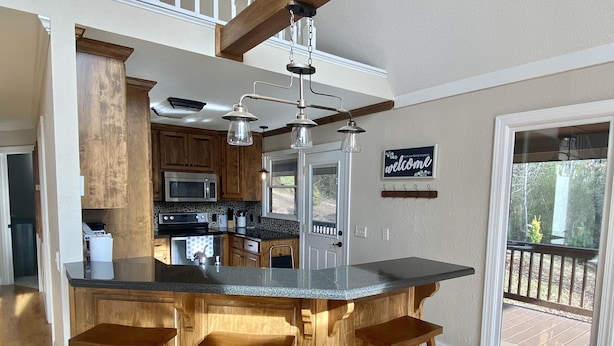 Una cocina con una isla grande, taburetes de madera, un microondas y un cartel que dice 'welcome'.