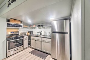 Enjoy cooking in this well-equipped kitchen with a refrigerator, oven, and toaster, plus a sink and pantry with shelves.
