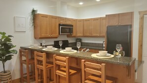 A kitchen with wooden cabinets, a granite countertop, and bar stools.
