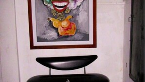 A framed artwork with a colorful abstract design on a wall, a black bench with a small table, and a door to the right. - 2G2-2 Apartamento en la Ciudad Antigua (Cartagena)