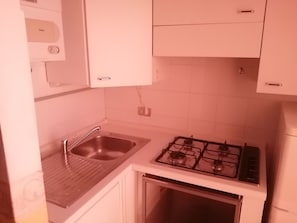 Een koelkast, kookgerei, borden en bestek, eettafels