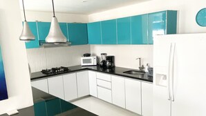 Une cuisine moderne avec des armoires de couleur turquoise, un plan de travail noir, un réfrigérateur blanc et un four à micro-ondes.
