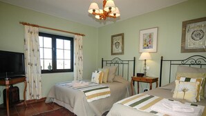 Un dormitorio con dos camas, televisión, ventana con cortinas, un reloj y obras de arte en las paredes.