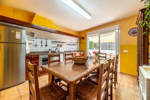 Una cocina con una mesa y sillas de madera, un refrigerador y un reloj en la pared.