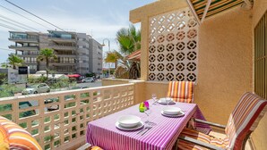 Un balcon avec une table dressée pour deux personnes, un mur décoré de motifs et une vue sur un immeuble situé de l’autre côté de la rue.