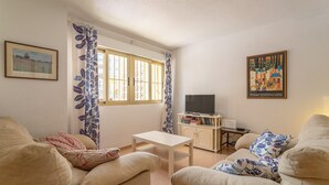 Un salon comprenant un canapé, une table basse, un téléviseur et une bibliothèque.