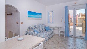 Ein Zimmer mit einer Couch, einem Tisch, einem Fenster und einer Tür zu einem Außenbereich.