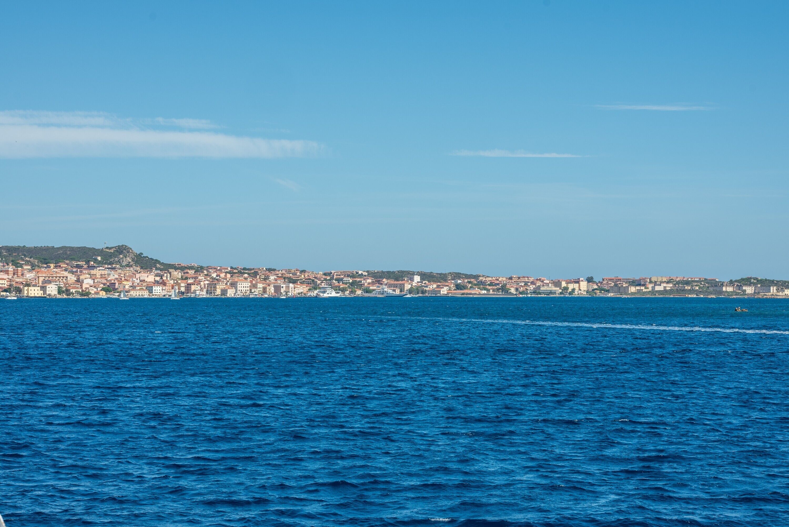 Eine Küstenstadt mit Blick auf das Meer und eine entfernte Hügelkette.