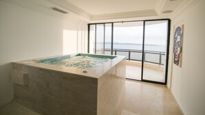 A spa room with a hot tub, a balcony with a view of the sea, and a painting on the wall. - Luxury 8 Bedroom Penthouse with Private Jacuzzi (Cartagena)