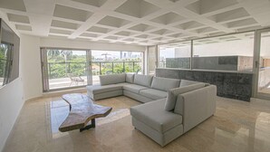 A modern living room with a sectional sofa, a unique coffee table, and a balcony with a view of the city. - 7 Bedroom Luxury Full Floor Apartment with Private Pool (Cartagena)