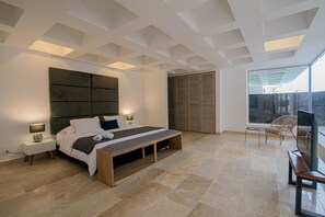 Ein modernes Schlafzimmer mit einem großen Bett, Nachttischen, einer Bank, einem Fernseher und einem Schiebetürenschrank.