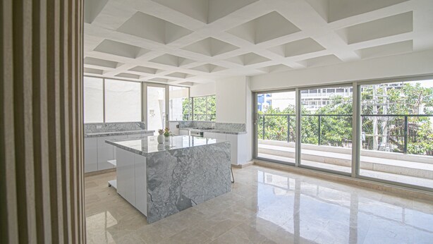 A modern kitchen with a marble island, large windows, and a balcony with a city view. - 7 Bedroom Luxury Full Floor Apartment with Private Pool (Cartagena)