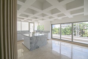Eine moderne Küche mit einer Marmor-Kochinsel, großen Fenstern und einem Balkon mit Blick auf die Stadt.