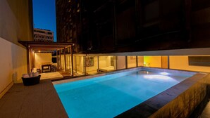 A modern outdoor pool area with a glass enclosure, a seating area, and a view of a building in the background. - 7 Bedroom Luxury Full Floor Apartment with Private Pool (Cartagena)