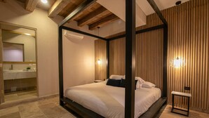 Una cama con dosel de madera, una mesita de noche y un buró.