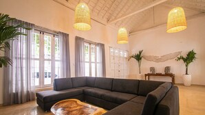 A spacious living room with a large sectional sofa, a wooden coffee table, and three hanging wicker lamps.