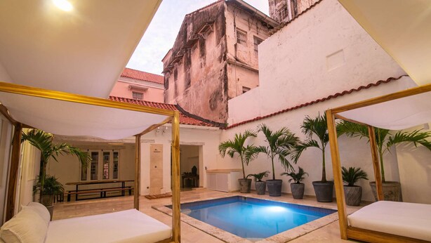 A poolside area with a small pool, two lounge chairs, and several potted plants.